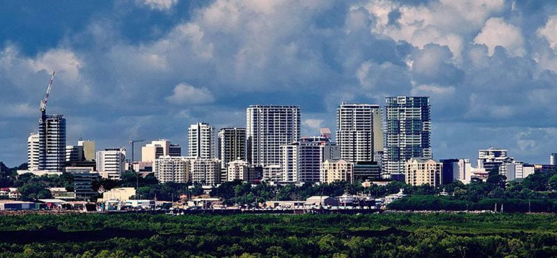 Image of the Darwin city skyline with blue, cloudy skies and green dense forest in the foreground