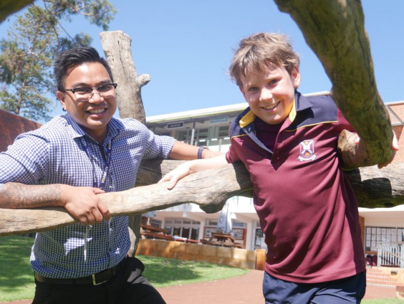 VisAbility occupational therapist Jeru Lopez stands next to Harry Nicholls in the open play area outside Scotch College.