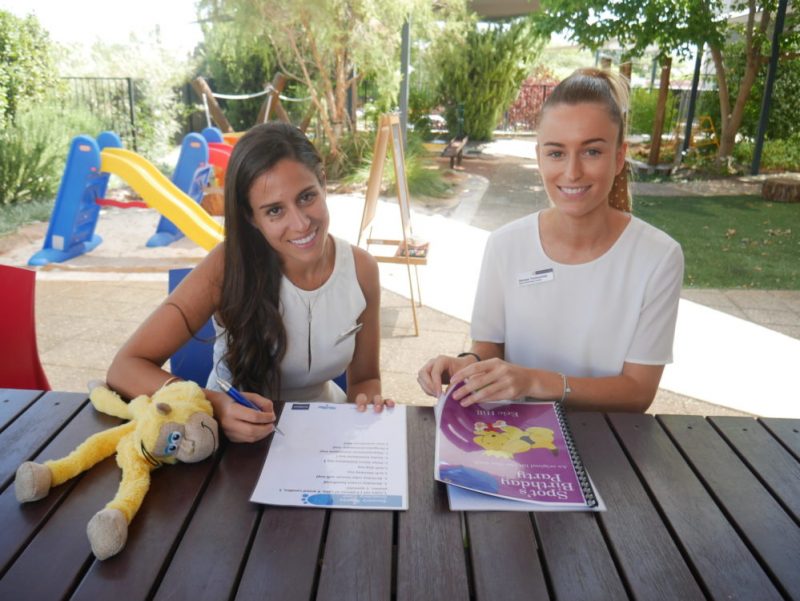 Katherine and Georgia seated at a bench with a toy and looking at paperwork.