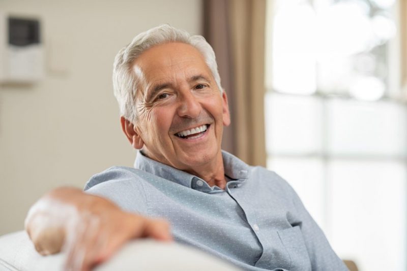 Smiling man with grey hair sitting on sofa