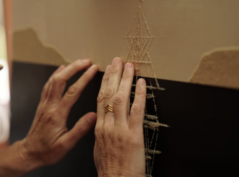 Image shows a person touching the painting and feeling the sand on the tall ship