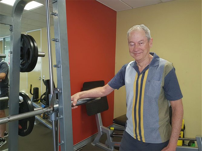 John in his workout gear next to some exercise equipment