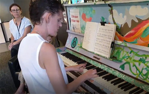 Image shows Tamara seated at a piano playing the keyboard