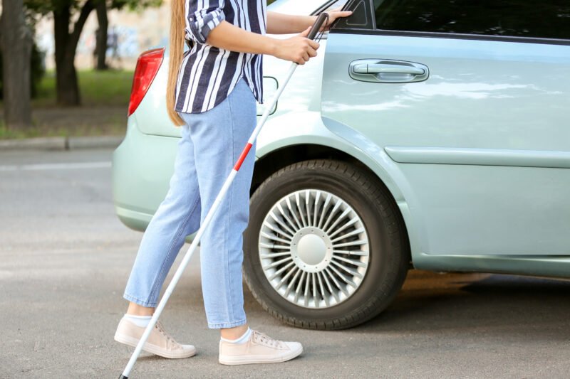 A woman with a white cane opens door of car 