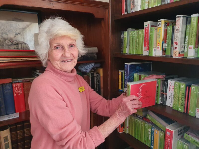 Hilary takes some audio books out of the book shelf 