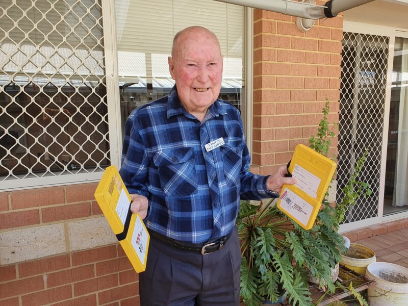 Mervyn stands in his garden with the audio books in each hand 