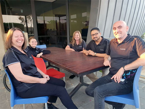 The CoAct VisAbility Team sit at a table in the VisAbility garden